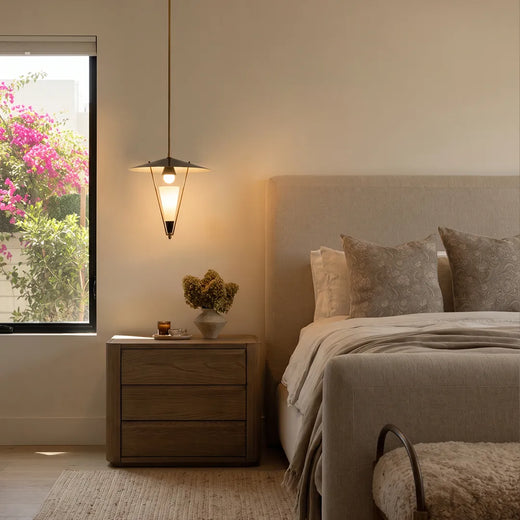 Mid century modern pendant light installed beside a bed with a wood nightstand in a cozy bedroom.