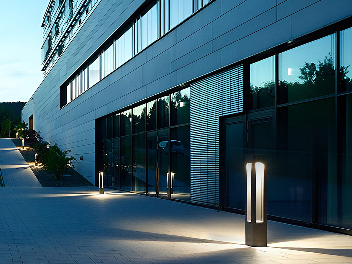 modern open-frame bollard light illuminating a contemporary building walkway at night