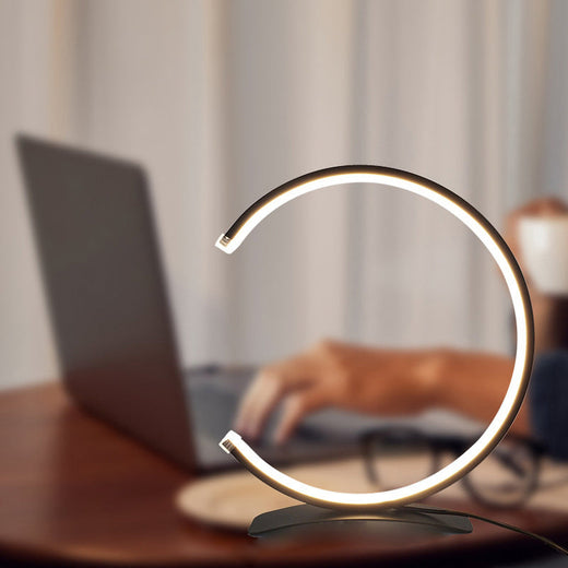 C shaped table lamp with a close-up of the illuminated curved head.