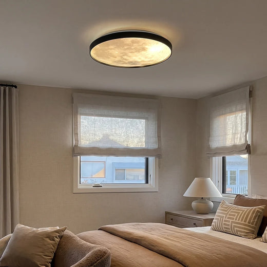 Moon ceiling light mounted on a bedroom ceiling, illuminating a soft neutral space with windows and bedside decor.