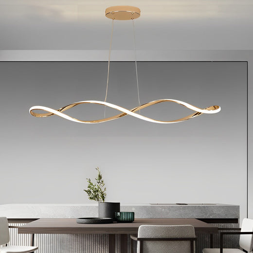 Waveform pendant light in gold finish hanging above dining table with modern decor.