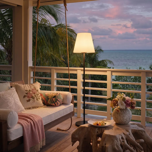 Modern outdoor floor lamp illuminating a covered balcony lounge with an ocean view.