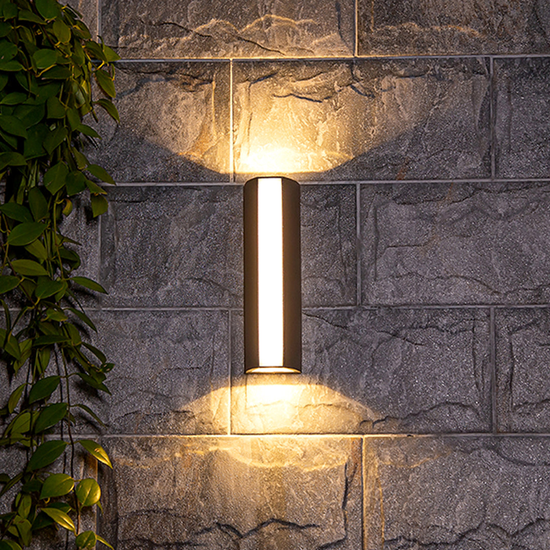Outdoor wall light casting warm golden glow on brick surface with dramatic shadow effects