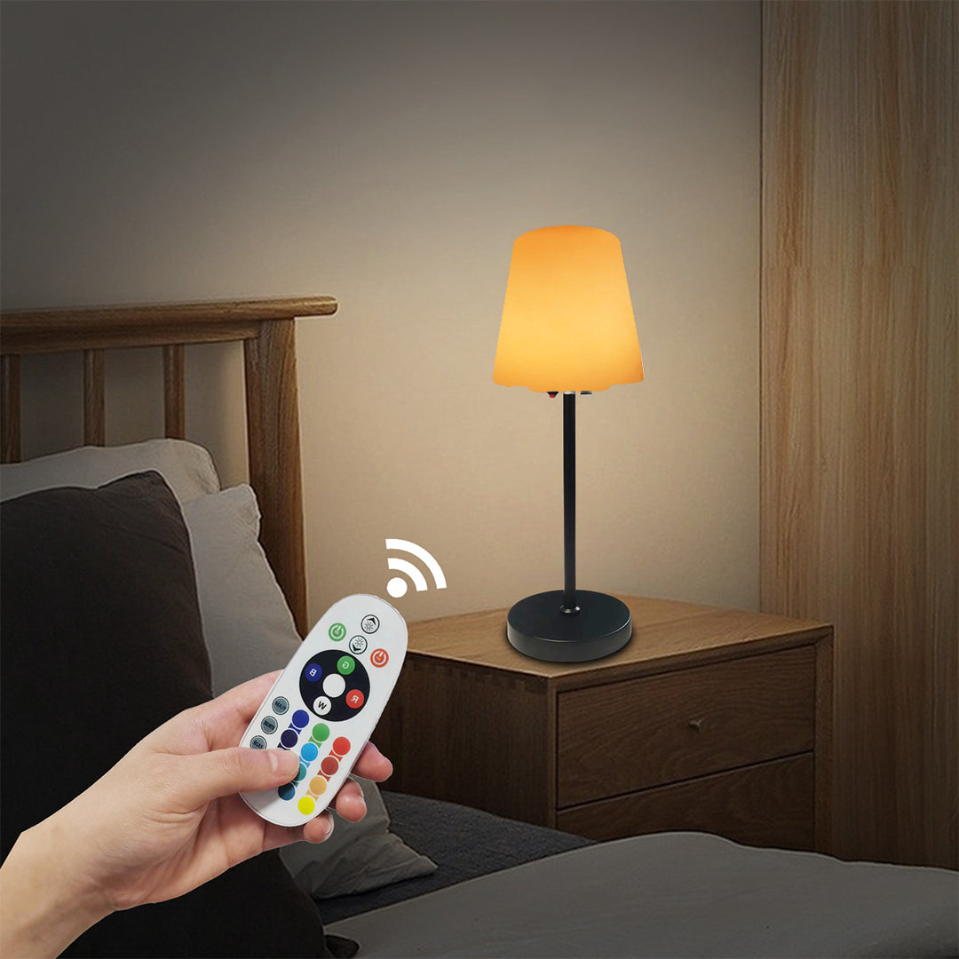 Hand holding remote control to adjust brightness settings of modern cordless table lamp