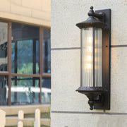 Traditional outdoor lantern with cylindrical ribbed glass shade providing ambient lighting on building facade