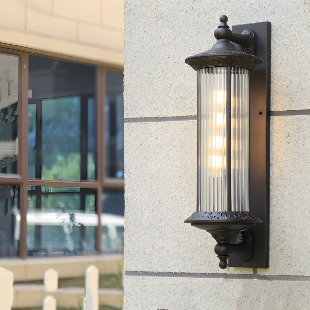 Traditional outdoor lantern with cylindrical ribbed glass shade providing ambient lighting on building facade