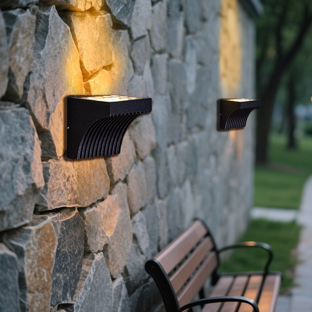 Traditional brass wall lantern with frosted glass shade mounted on stone exterior wall