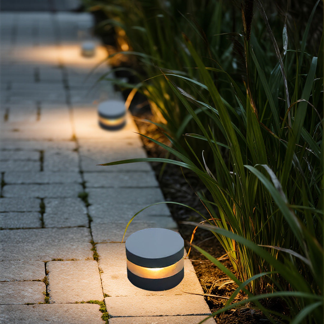 110v landscape lights lining a paved walkway, guiding the path with warm and subtle illumination at dusk.