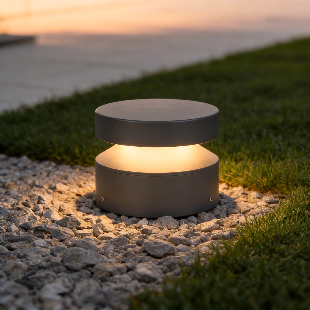 Close-up of a 110v landscape light on stone ground, highlighting its soft diffused glow and modern cylindrical shape.