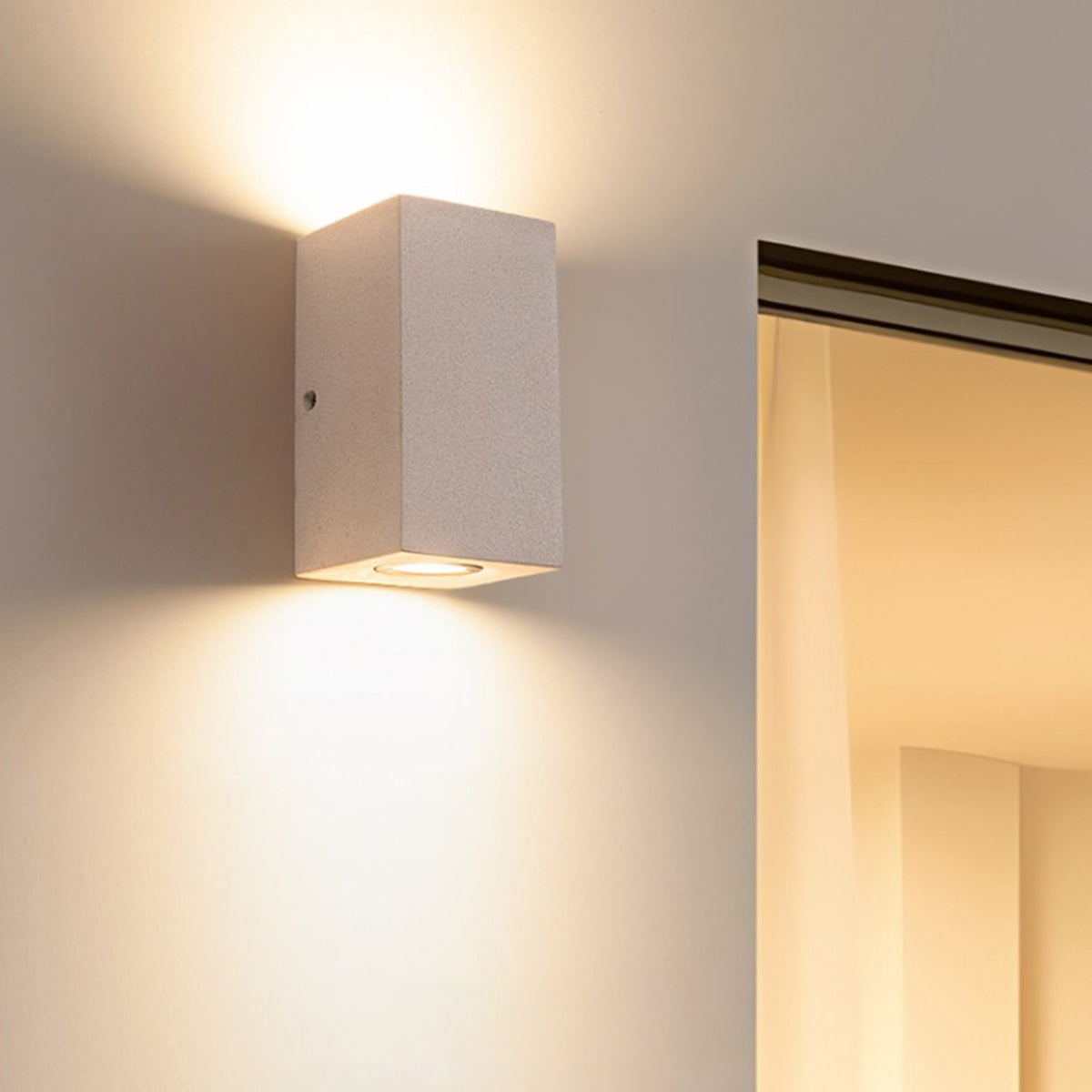 Cubic concrete light fixture with warm LED creating dramatic shadow and light interplay