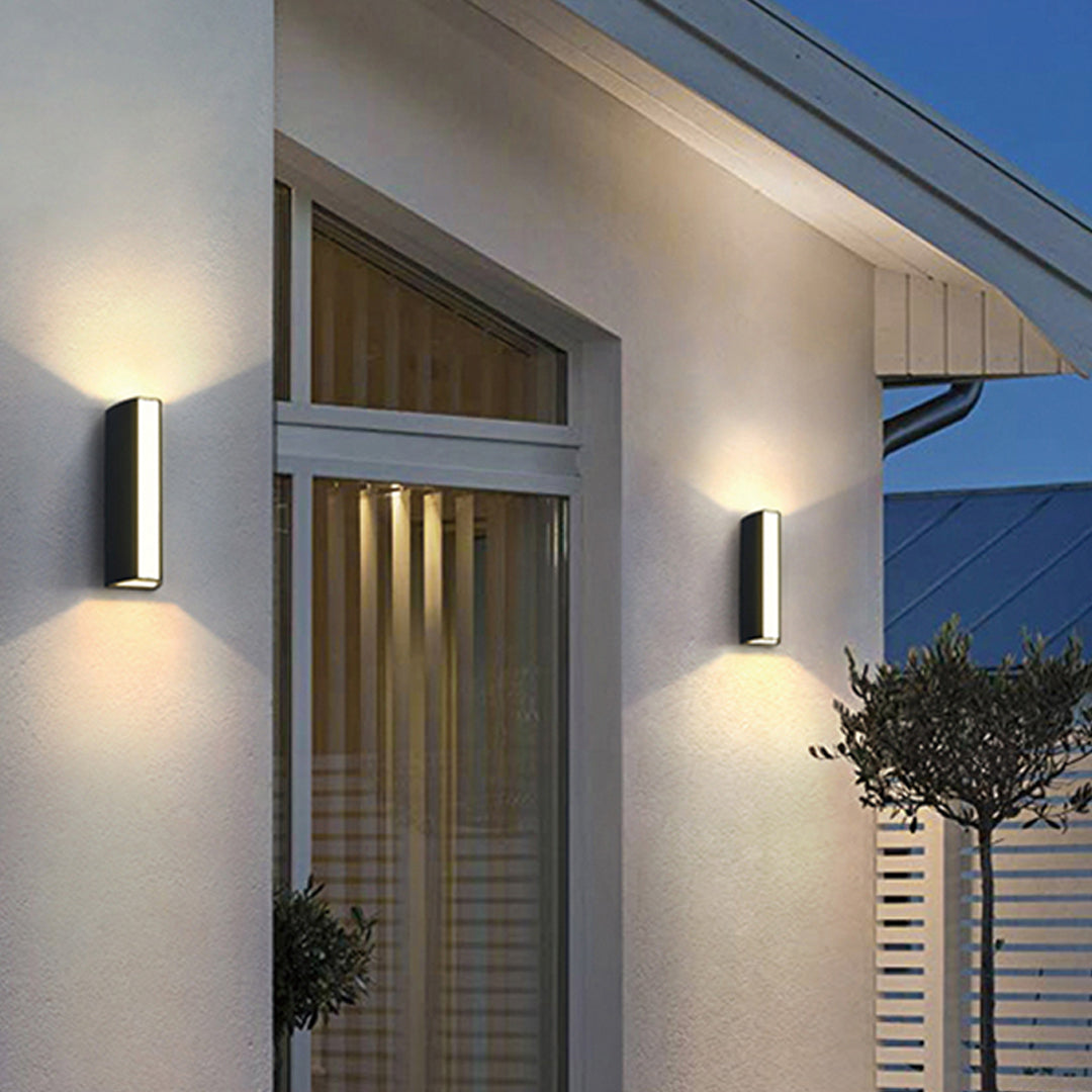 Outdoor wall light casting warm golden glow on brick surface with dramatic shadow effects