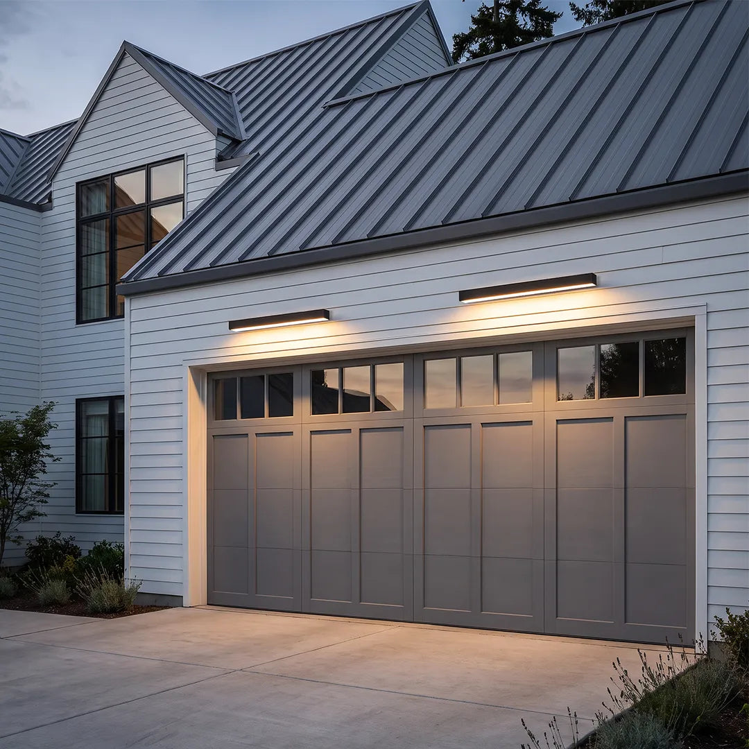 Exterior porch light fixtures mounted above a double garage door on a white farmhouse exterior.