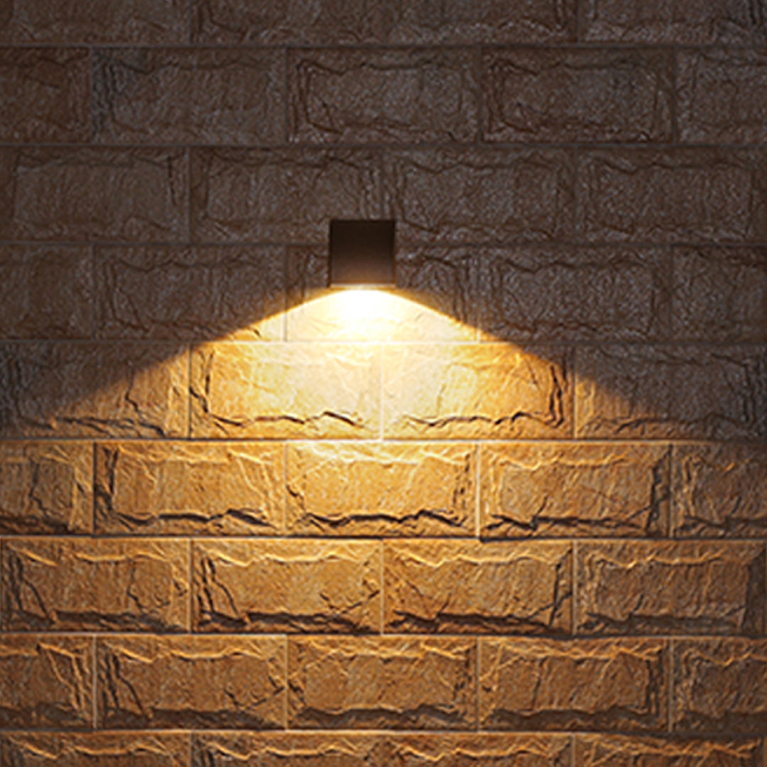Traditional brass wall lantern with frosted glass shade mounted on stone exterior wall