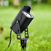 Adjustable garden spotlight with spike mount positioned on green lawn in daylight