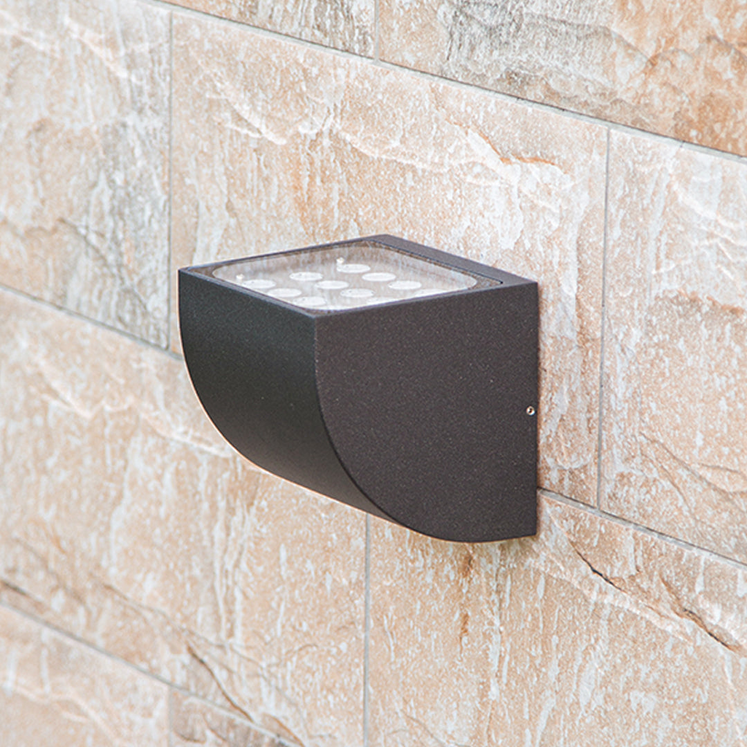 Traditional brass wall lantern with frosted glass shade mounted on stone exterior wall