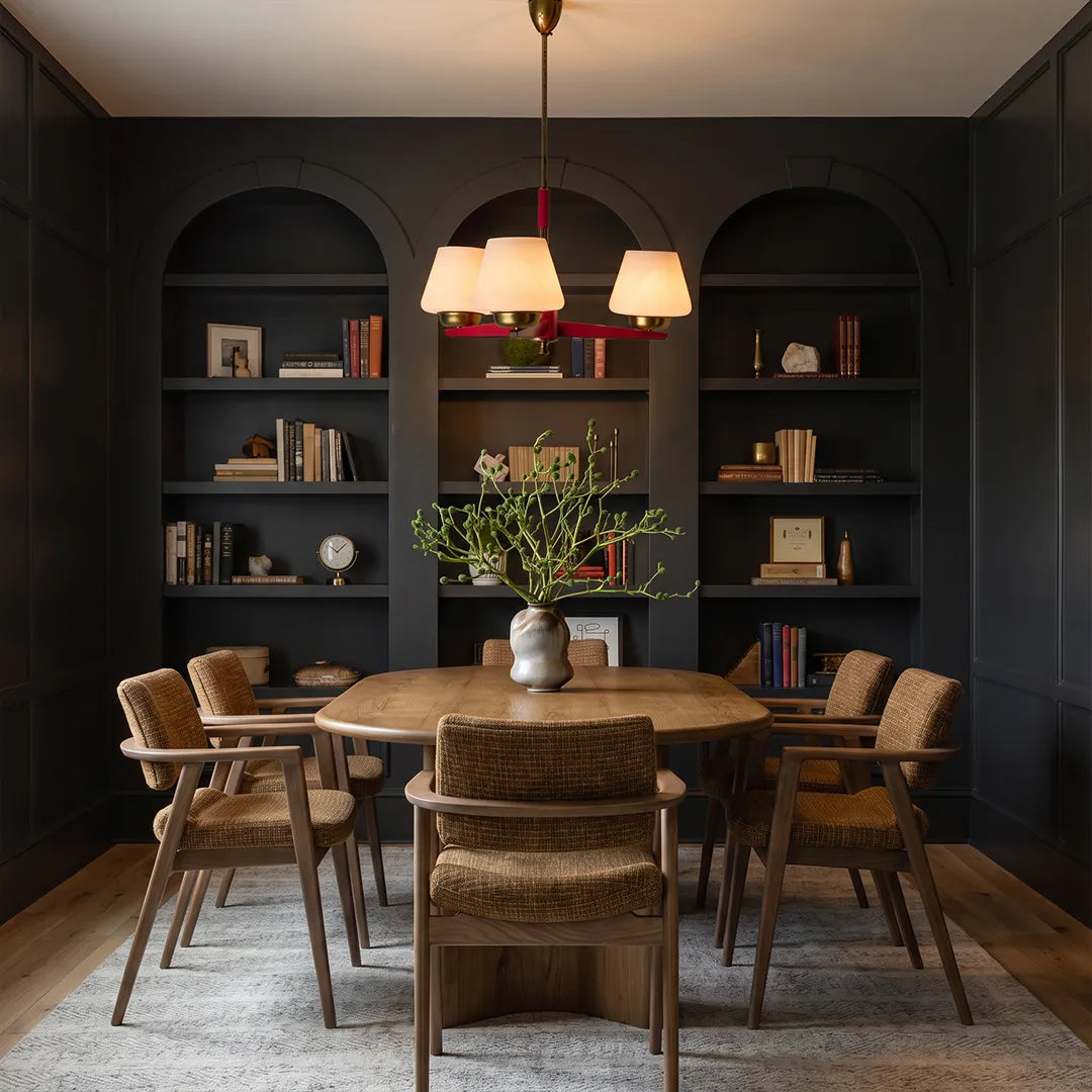 3 light chandeliers centered above a dining table in a dark built-in cabinet dining room.