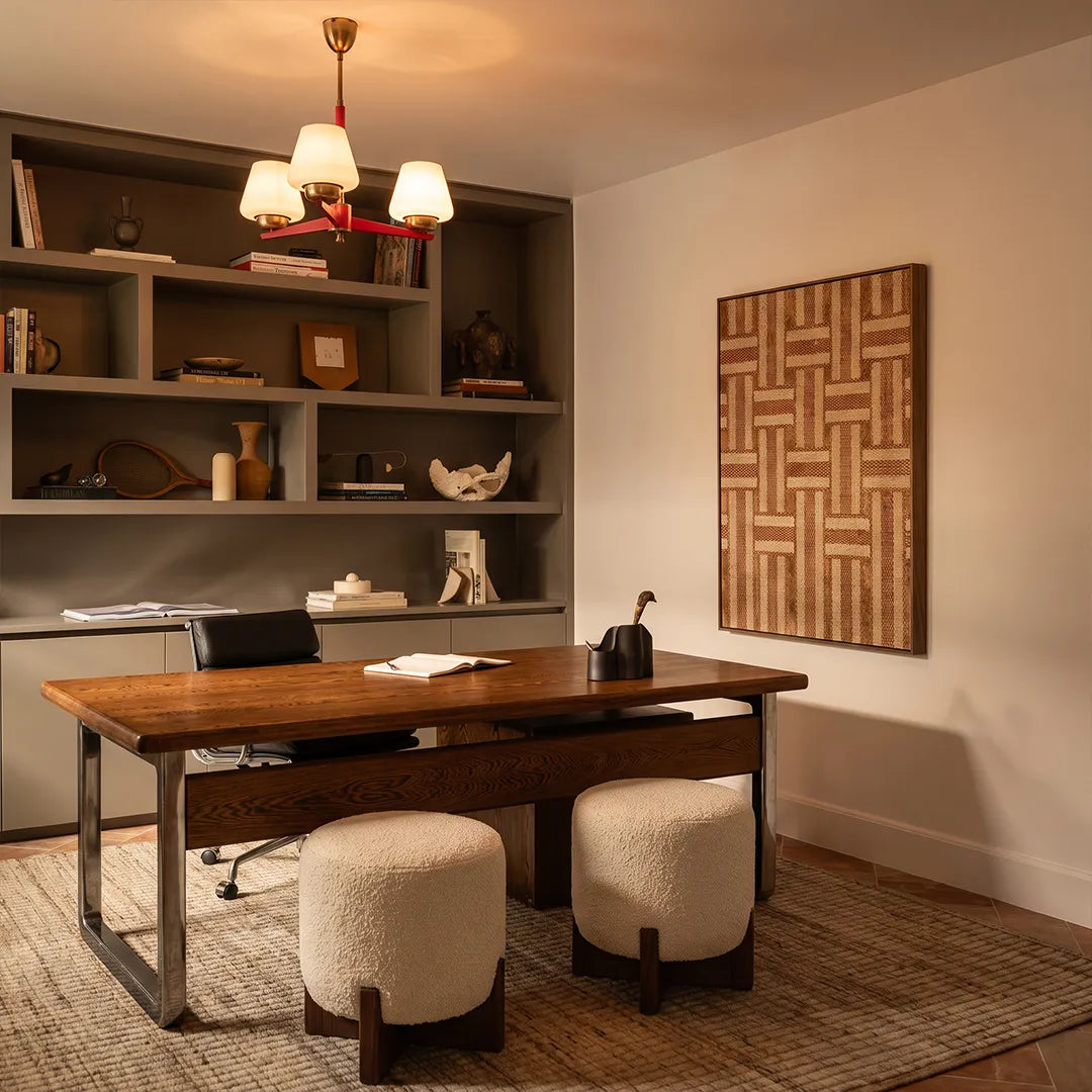 3 light chandeliers illuminating a home office with built-in shelves and a wooden desk.