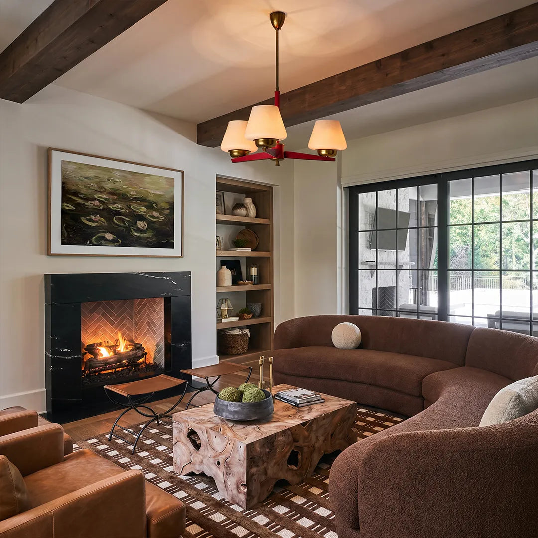 3 light chandeliers installed in a cozy living room with exposed beams and a fireplace.