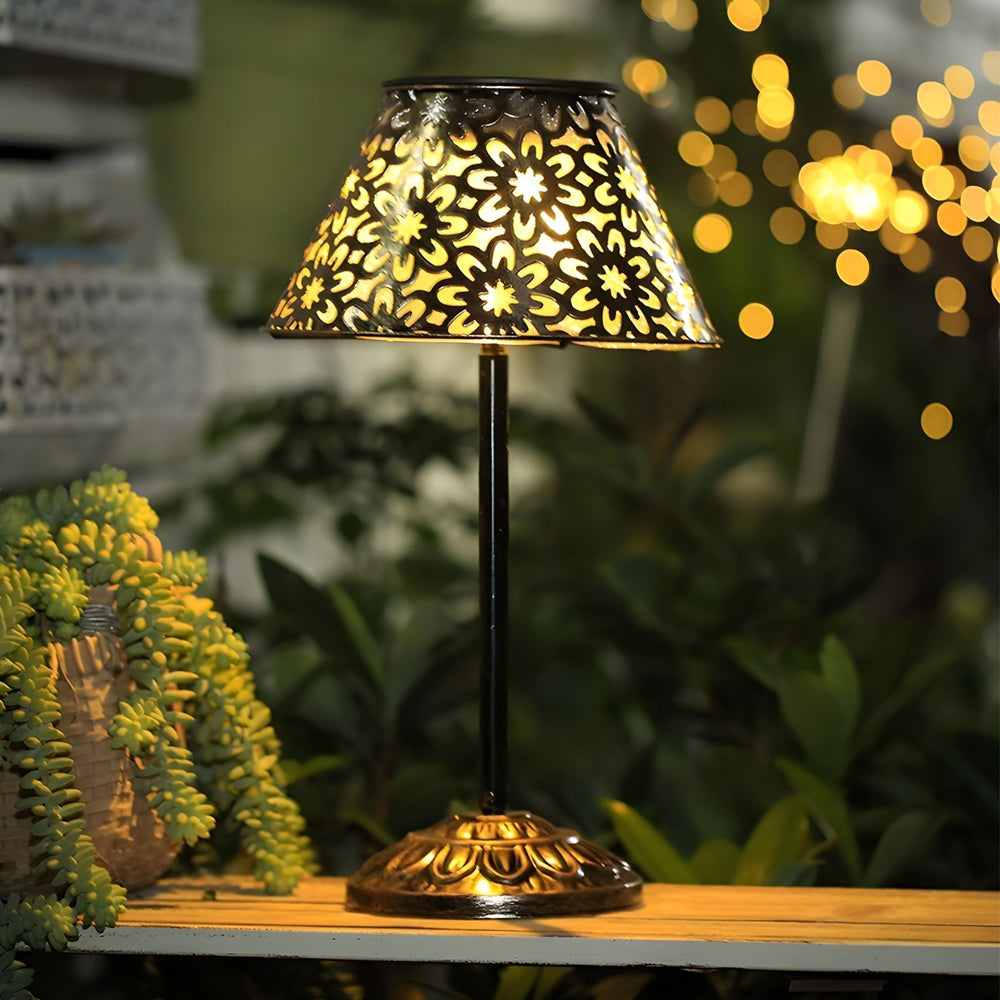 Garden table featuring illuminated solar lamp creating beautiful shadow patterns among potted plants at evening