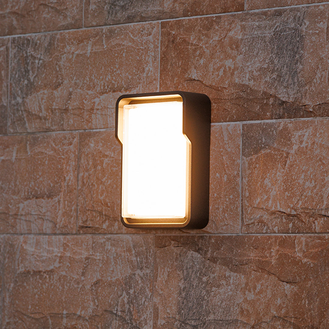 Contemporary outdoor wall light with horizontal slats mounted on building exterior fence area