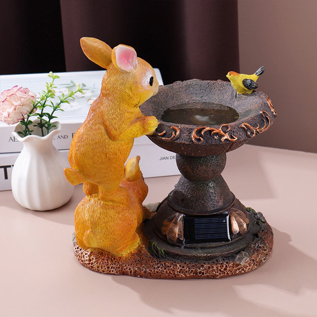 Two golden rabbits gathered around illuminated fountain with yellow butterflies on indoor display