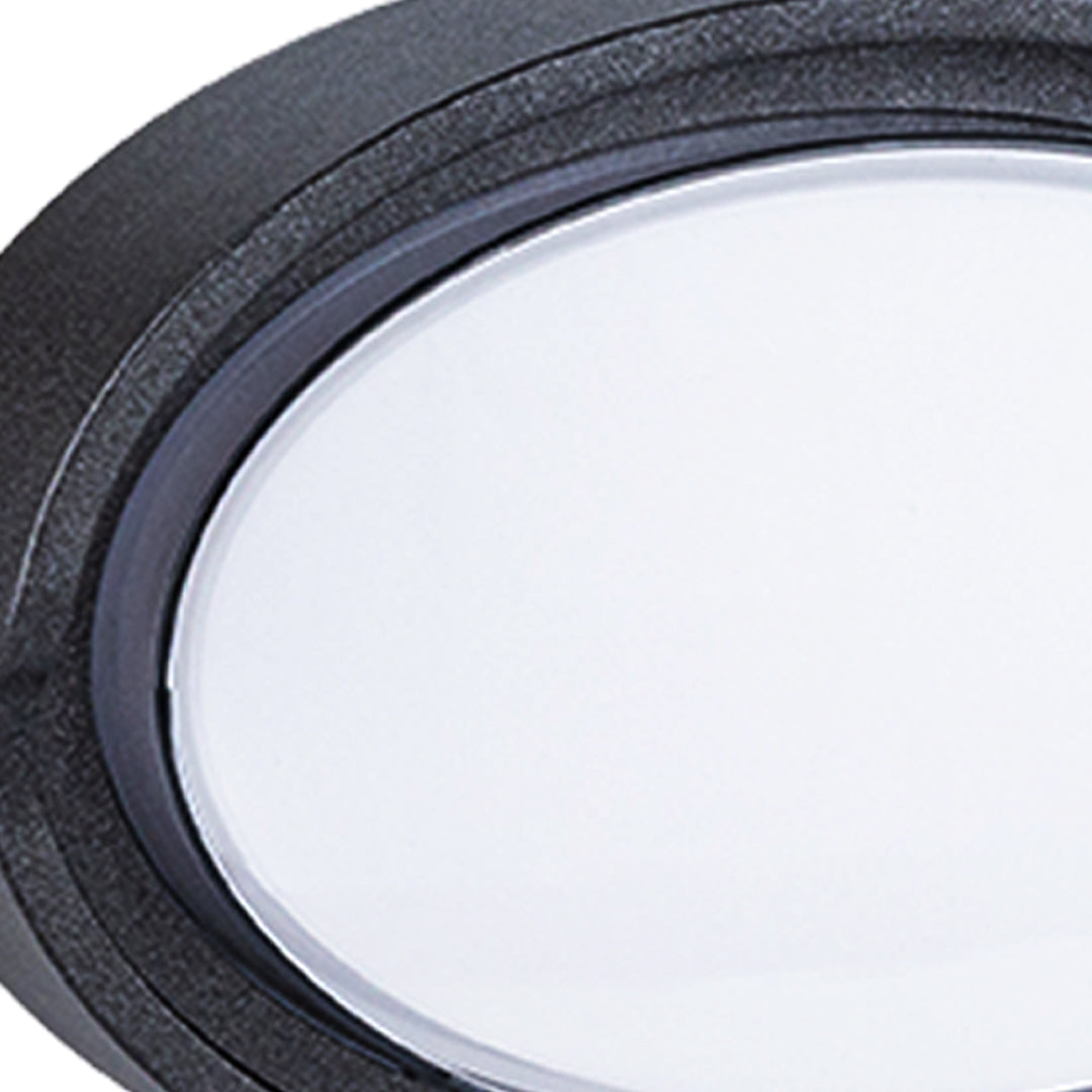 Round outdoor wall sconce with frosted diffuser creating ambient lighting on building exterior