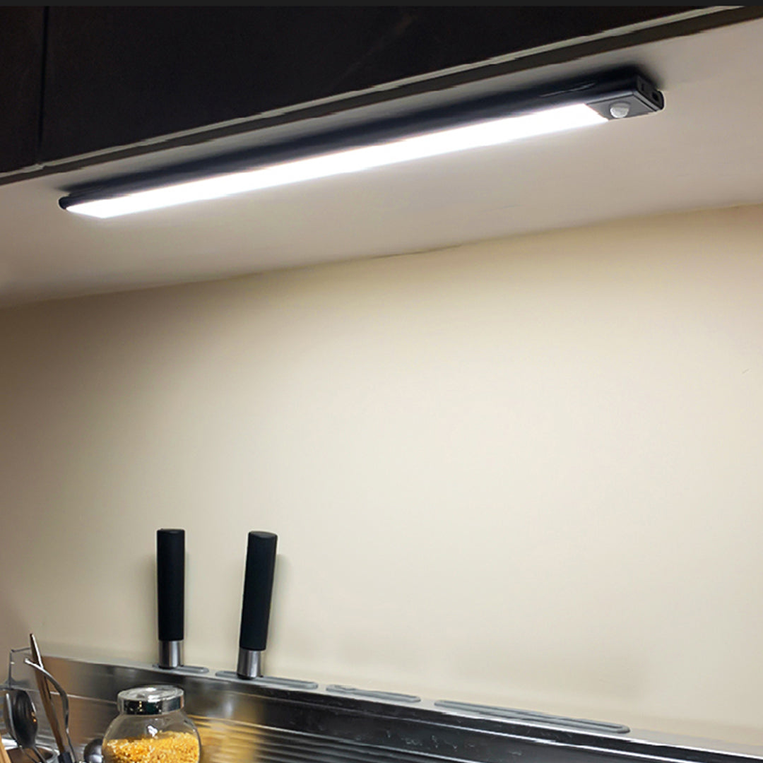 Slim LED strip light mounted under cabinet shelf providing bright white illumination in modern kitchen setting