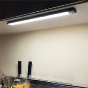 Slim LED strip light mounted under cabinet shelf providing bright white illumination in modern kitchen setting