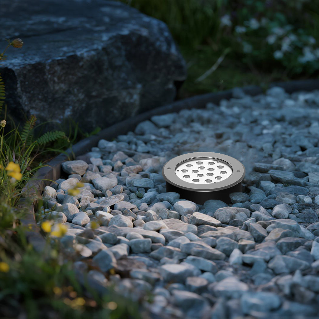 Modern in-ground light fixture with prismatic lens and metal housing for landscape accent lighting