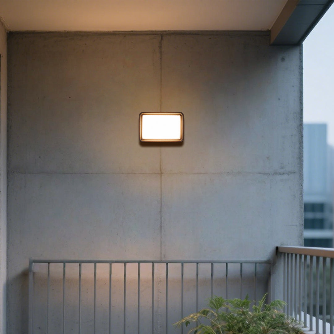 Outdoor wall light with angled black housing and directional beam capabilities