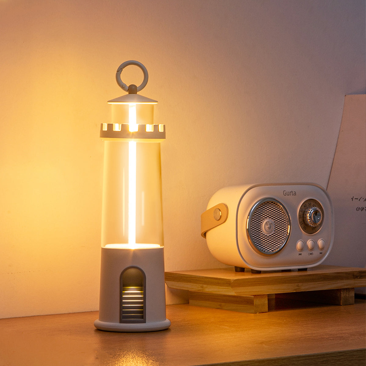 Cylindrical desk lamp with brass accents creating warm glow next to vintage radio on wooden surface
