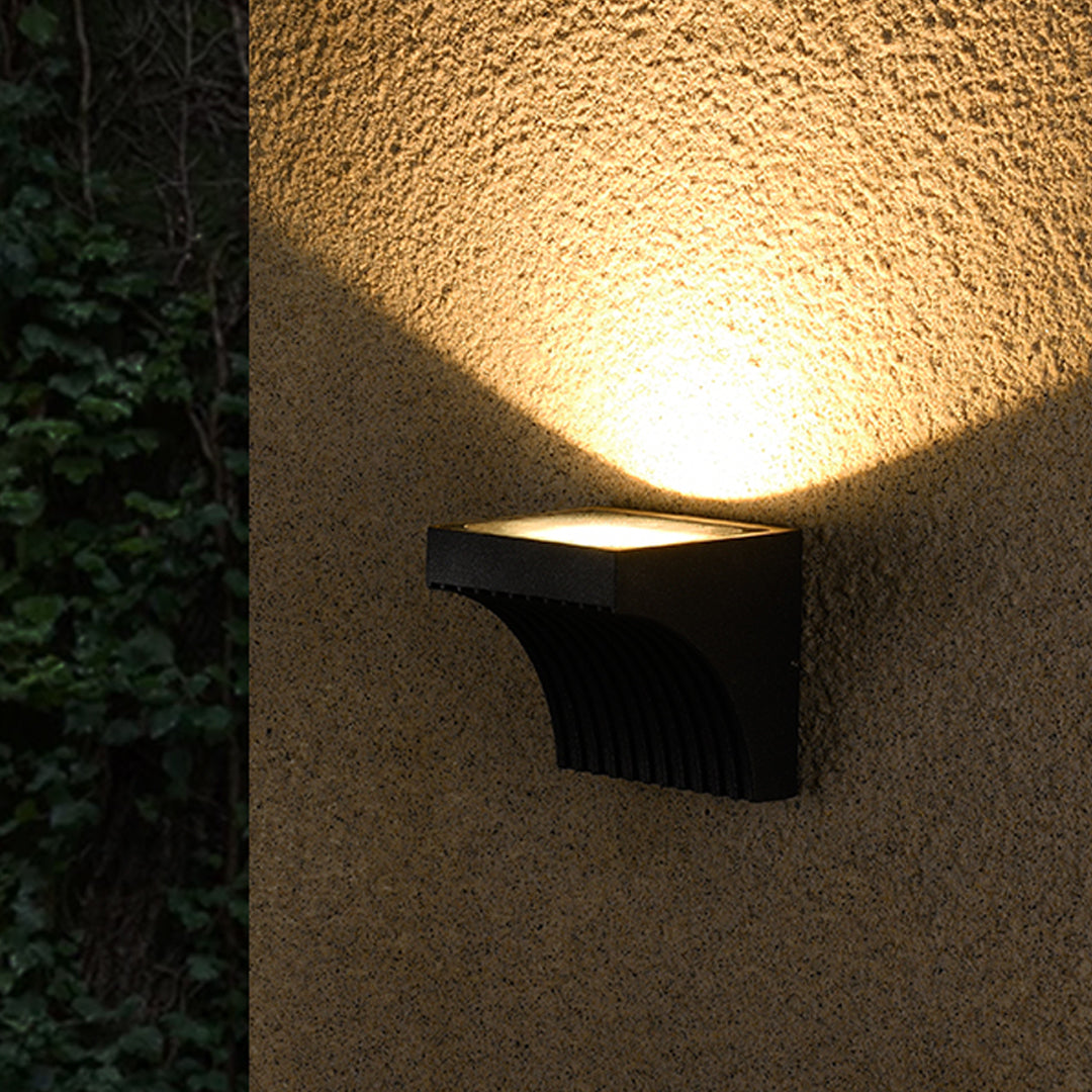 Close-up view of bronze outdoor light fixture showing curved arm and mounting details
