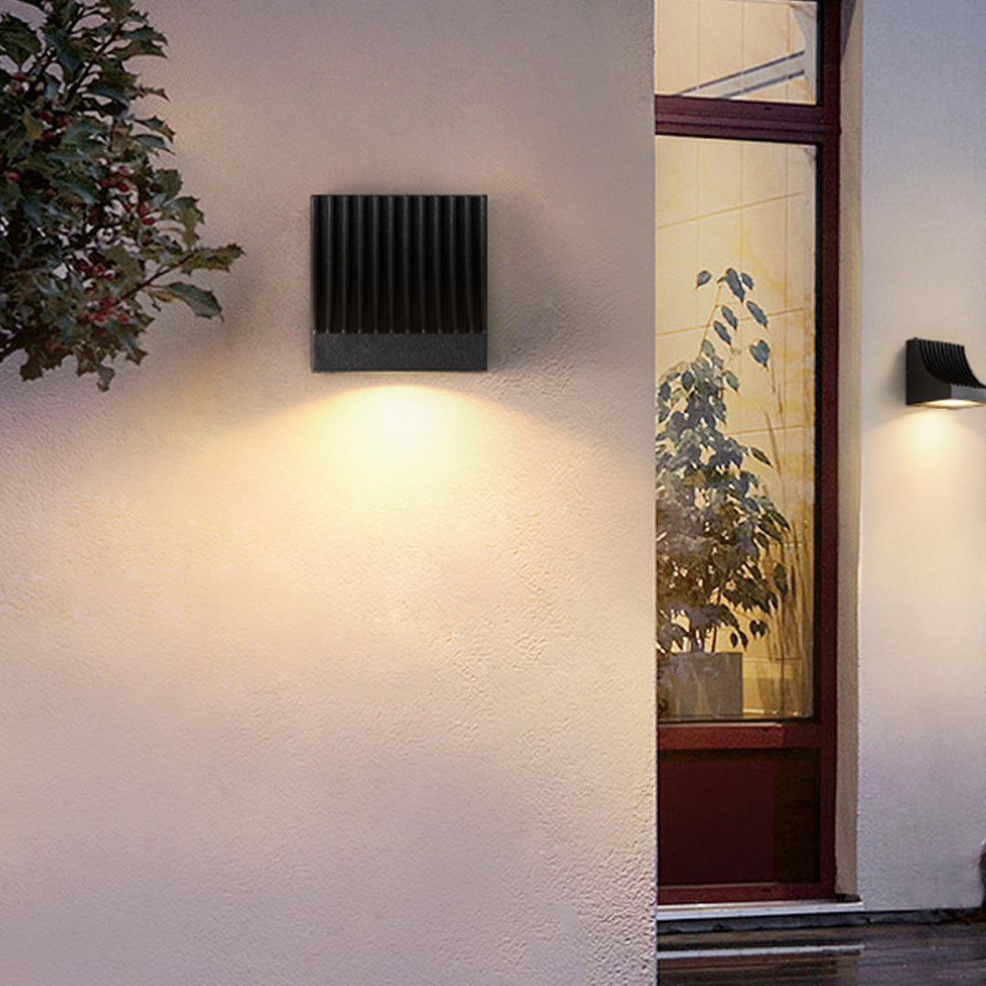 Traditional brass wall lantern with frosted glass shade mounted on stone exterior wall