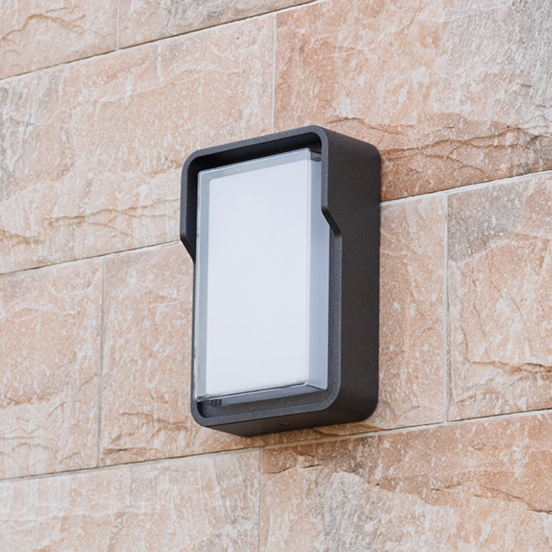 Contemporary outdoor wall light with horizontal slats mounted on building exterior fence area