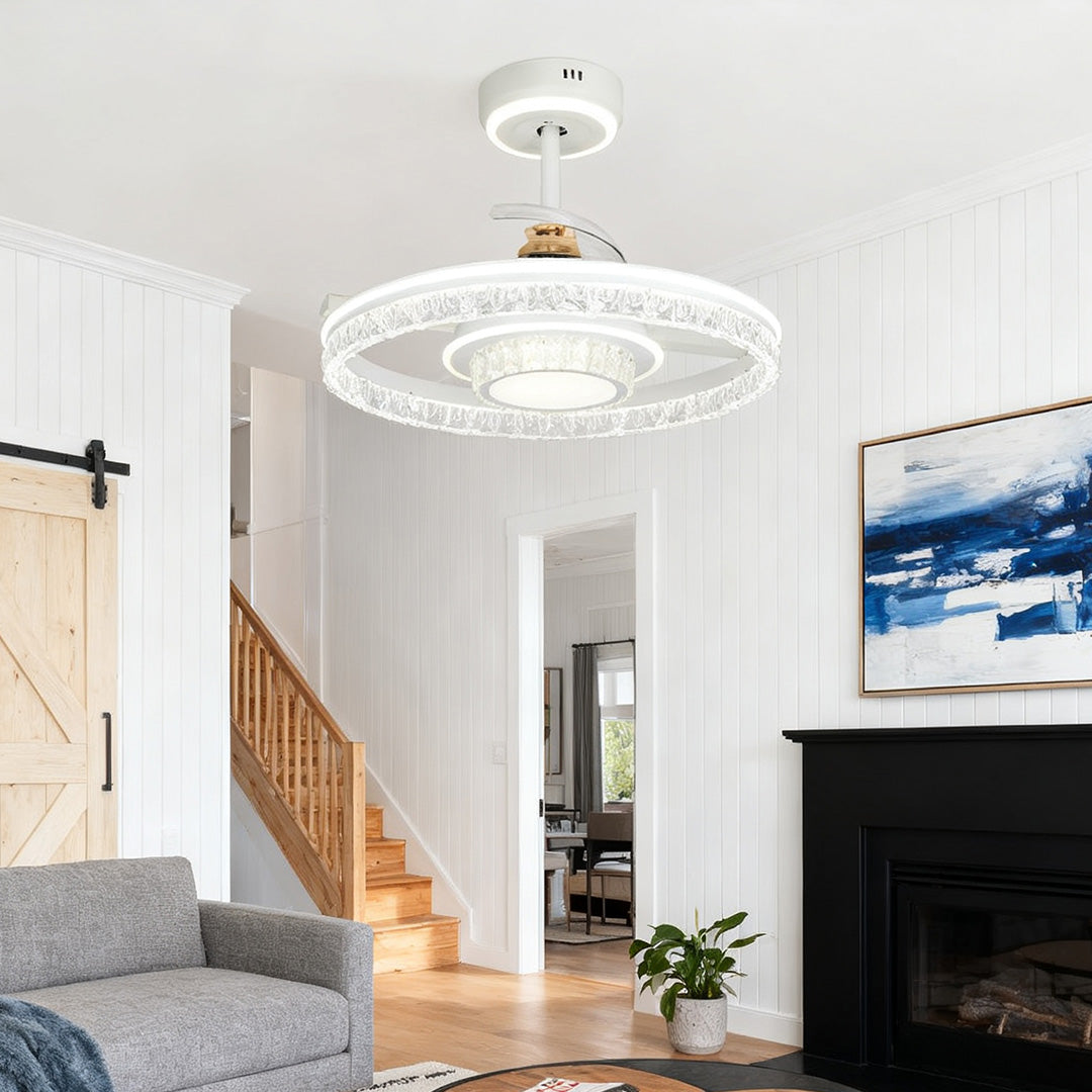 Ceiling fan with round light and crystal shade providing illumination in a cozy living room with a black fireplace and barn door leading to a staircase. 