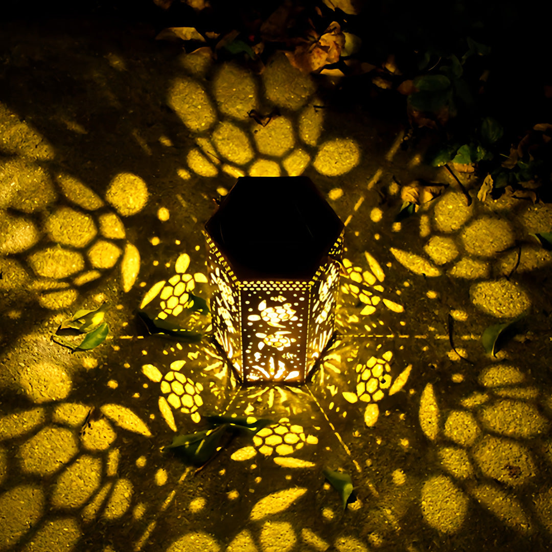 Decorative metal red outdoor lantern illuminating a patio floor with a warm, wide-spread light effect.