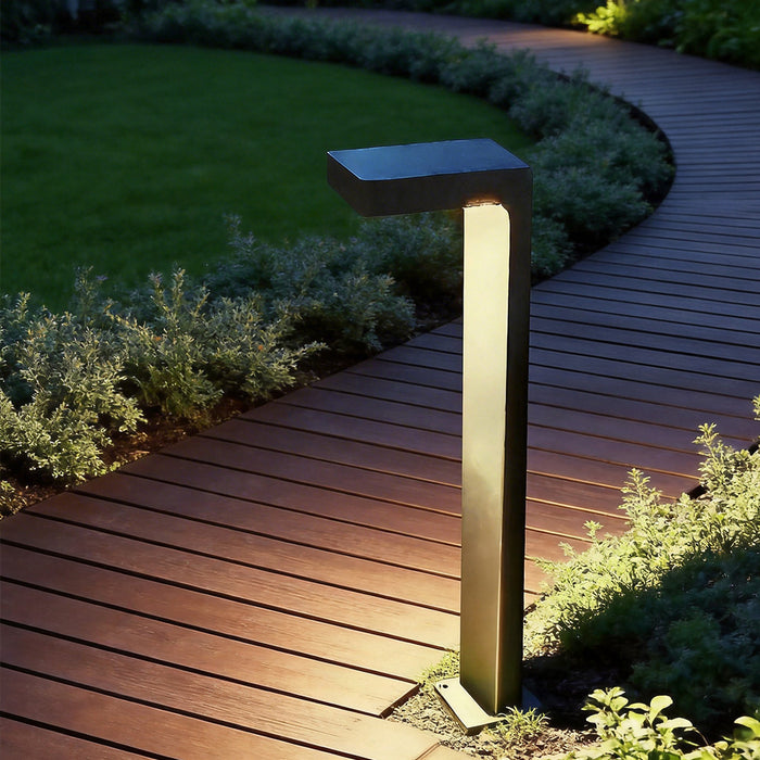 Modern black pathway bollard lighting beside a curved garden walkway, showing low-glare wayfinding after dark
