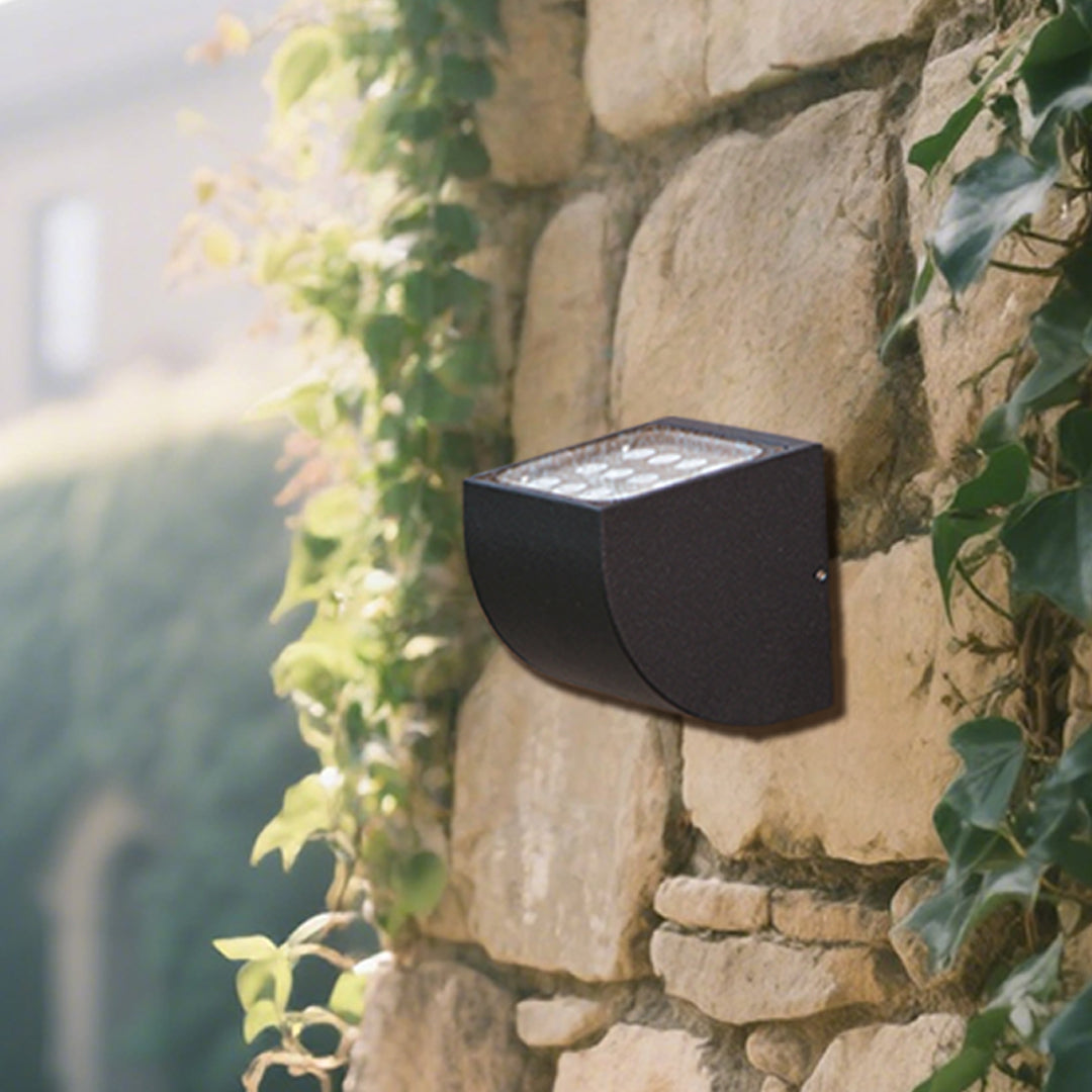 Traditional brass wall lantern with frosted glass shade mounted on stone exterior wall