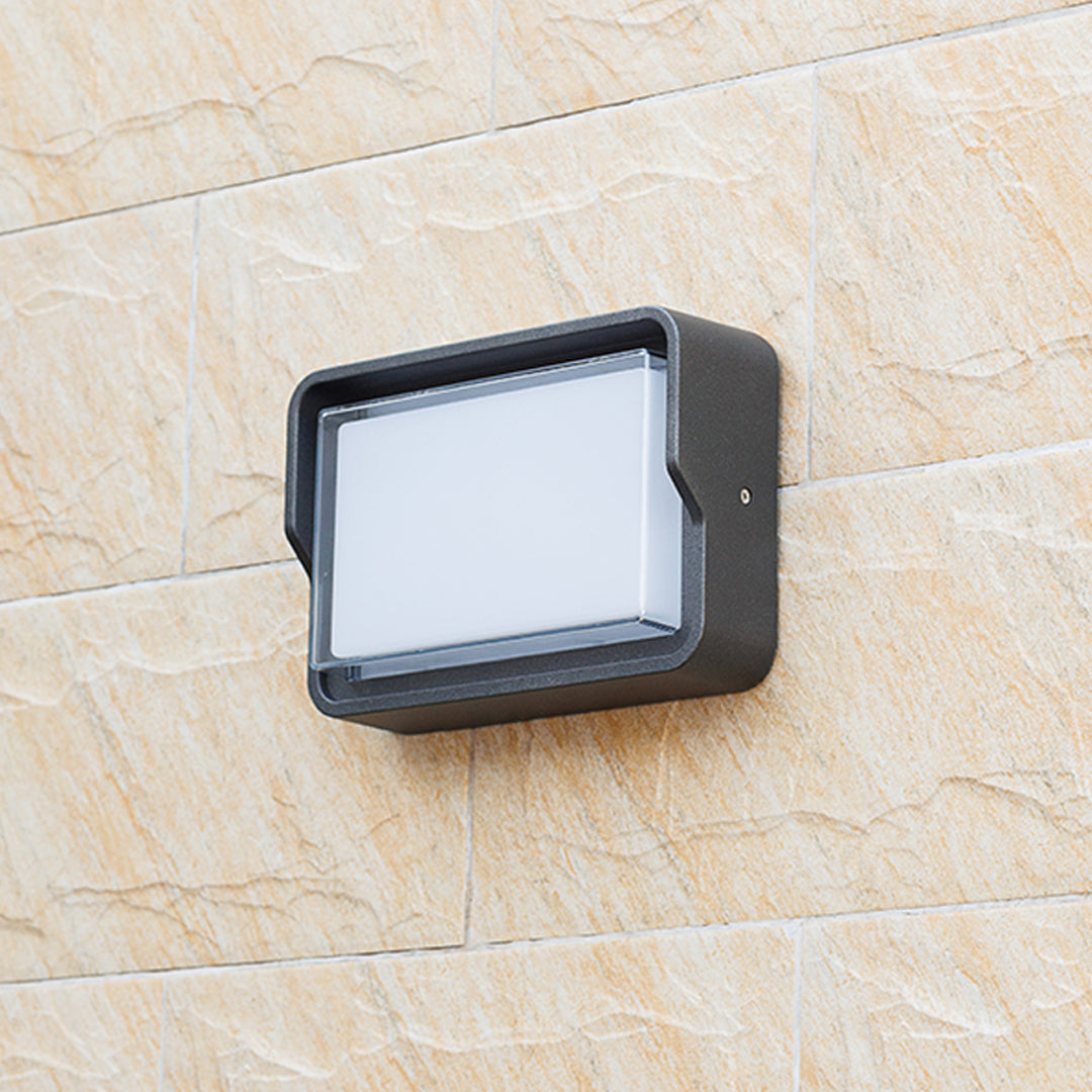 Outdoor wall light with angled black housing and directional beam capabilities
