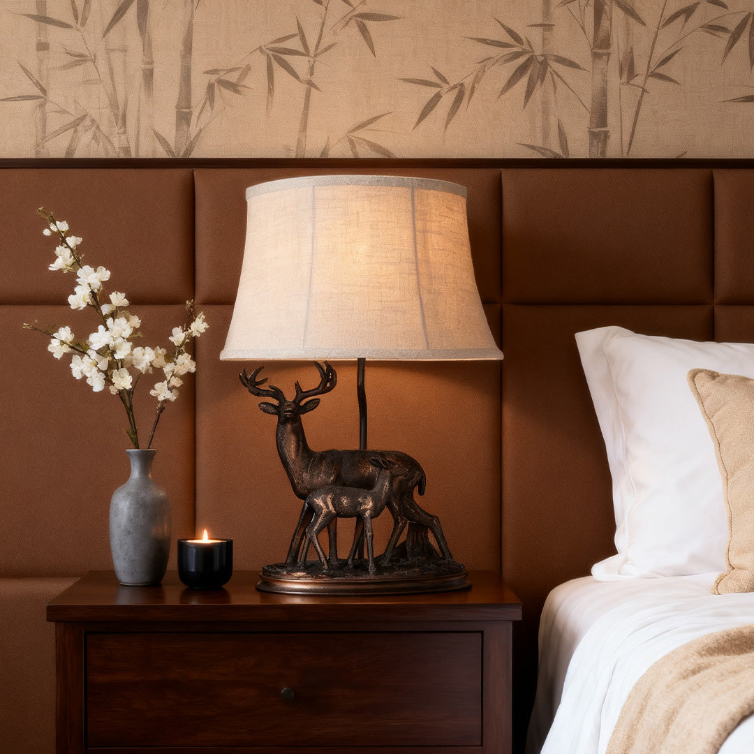 Accent deer table lamp providing soft ambient light on a dark wood nightstand in a cozy, nature-themed bedroom.
