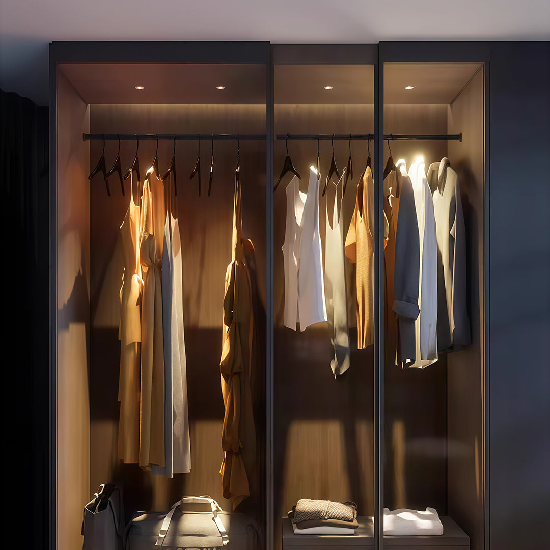 Accent spotlights highlighting luxury walk-in closet with glass doors and elegant clothing display
