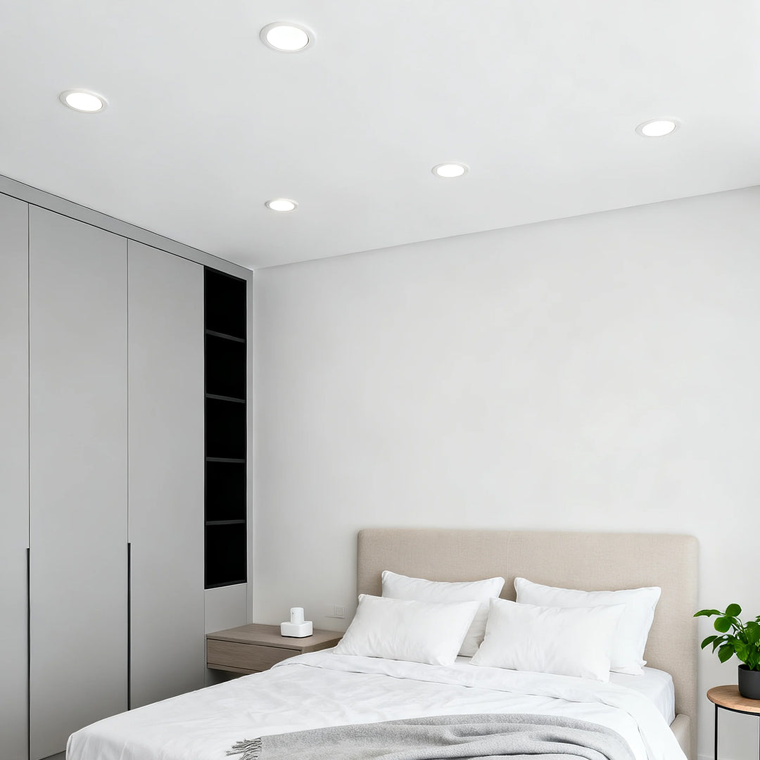 Accent spotlights creating soft illumination in serene white bedroom with minimalist decor