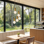 Acrylic bulb chandelier installed in modern cafe dining area with large windows.