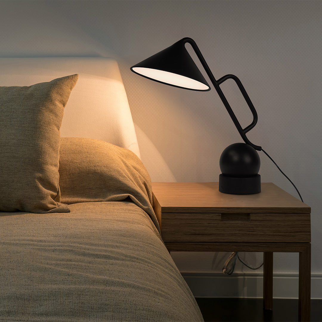 Adjustable black metal desk lamp providing warm ambient lighting for evening work sessions