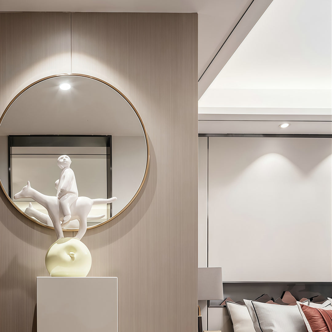 Adjustable downlights highlighting circular mirror and white sculpture in sophisticated neutral interior