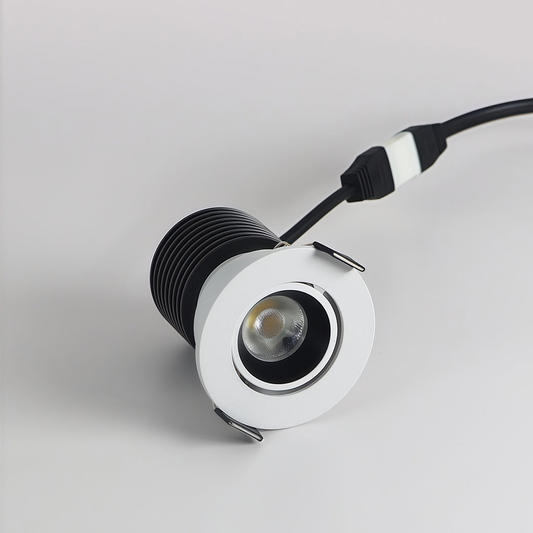 Adjustable indoor spotlights in white finish with tilting head and glass shade chandelier reflector for accent illumination.