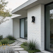 Adjustable outdoor wall light illuminating a modern house exterior with warm directional glow.