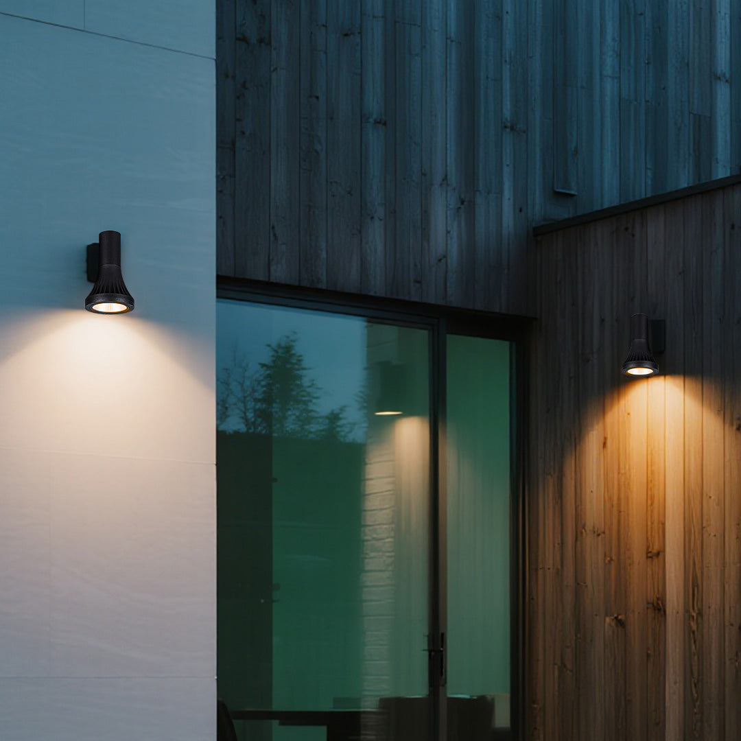 Warm exterior glow provided by adjustable up-down Outdoor Wall Lighting Fixtures near the large sliding glass door of a wooden home.