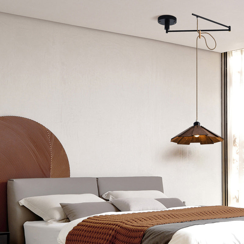 Adjustable pendant light fixture hanging beside a bedroom bed