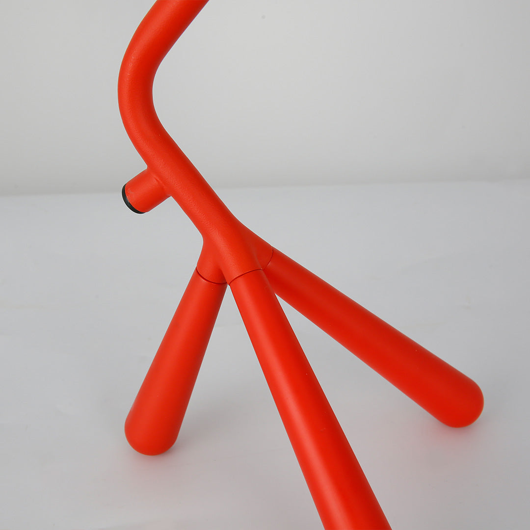 Adjustable three legged table lamp with red tripod base offering flexible lighting solutions